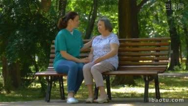 年轻护士在阳光明媚的日子里与老年妇女在公园<strong>长凳</strong>上聊天全高清慢动作镜头